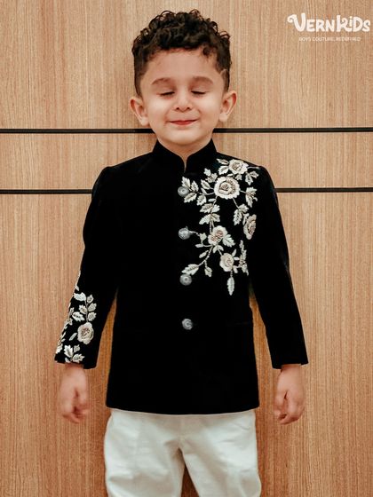The definition of sophistication. This little gentleman is stealing the show in our black velvet Indo-western jacket, featuring delicate white floral embroidery for a chic, monochrome look.