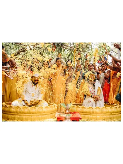The vibrant energy of a Haldi ceremony. I capture the joy and chaos as family and friends shower the couple with flowers and blessings, a key part of many Indian wedding traditions.