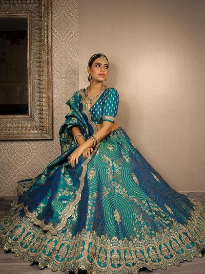 A regal shot of a model in our popular teal and gold lehenga. The pose highlights the grandness of the outfit, making it suitable for a bride's Sangeet or reception.