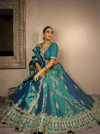 A regal shot of a model in our popular teal and gold lehenga. The pose highlights the grandness of the outfit, making it suitable for a bride's Sangeet or reception.