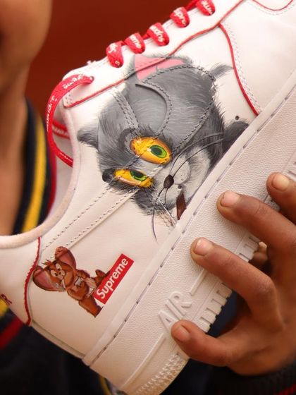 Another angle of the Tom and Jerry sneakers. This shot shows the playful interaction between the two characters, with Jerry peeking out from behind the Supreme logo.