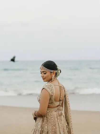 A back view showing the elegant floral bun and the delicate work on her blouse, perfect for a destination wedding.