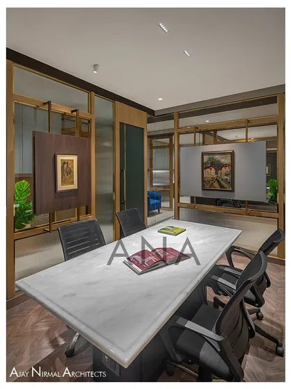The conference room at Jain Cosphere Office is designed for 4-6 people, with a glass partition that uses both clear and fluted glass for privacy. A central panel is cleverly utilized to display artwork.