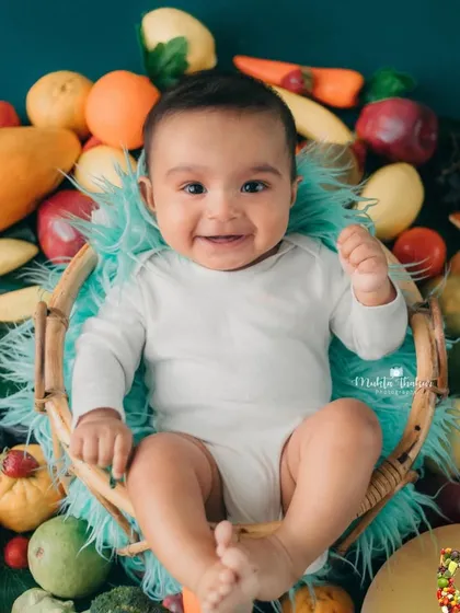 A little heaven on earth. This smiling 5-month-old is surrounded by a rainbow of healthy fruits and vegetables.