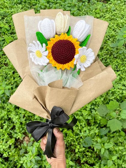 I love how this rustic bouquet turned out. It combines a bright crochet sunflower with white tulips and daisies, all wrapped in simple brown craft paper with a black ribbon. It has such a natural and charming feel.