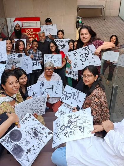 Participants of a calligraphy workshop proudly display their Devanagari script artwork. Our workshops are hands-on, creative, and result in beautiful work you can take home.