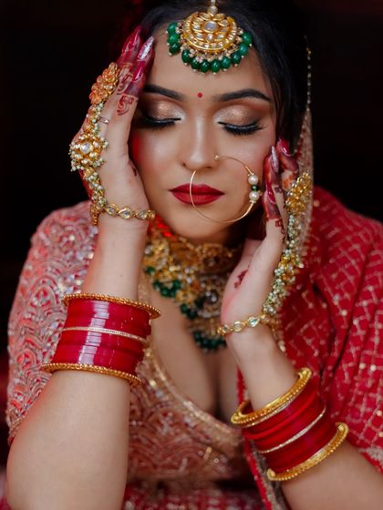 This expressive pose highlights the traditional red bangles (chooda) and the rich bridal jewelry.