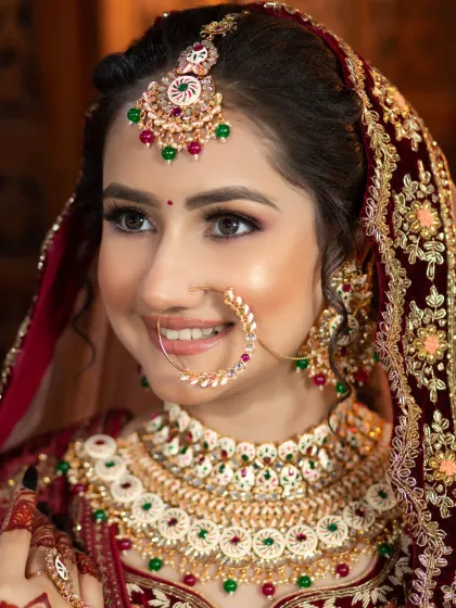 A close-up of a smiling bride. Her makeup features a flawless base and subtly defined eyes, letting her natural happiness shine through.