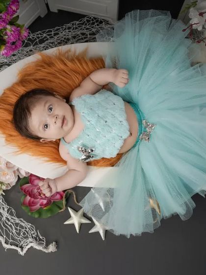 A little fashionista in the making. This baby girl is dressed in a beautiful blue tutu, looking calm and content during her styled studio session.