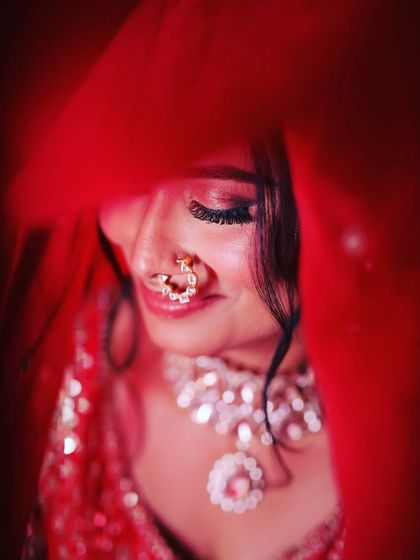 A close-up of a bride peeking through her red veil, a classic and intimate shot.