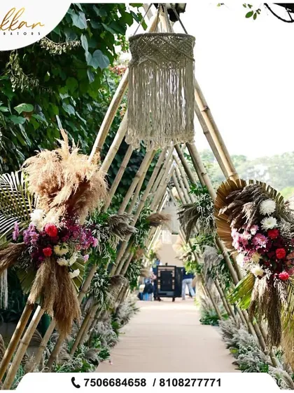 A rustic and enchanting entryway made from bamboo poles and decorated with pampas grass and floral arrangements. The macrame lantern adds a bohemian touch.