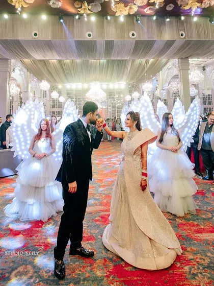 The couple's grand reception entrance, flanked by performers dressed as angels with illuminated wings.