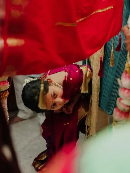 A child peeking from under the Antarpat during a Maharashtrian wedding. These curious, candid moments from the little guests add so much charm to the wedding album.