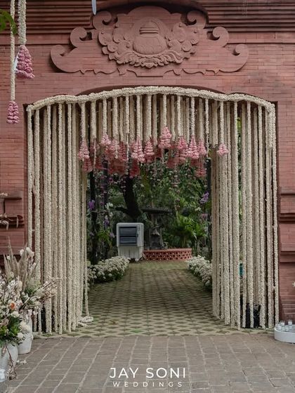 A dreamy wedding entrance filled with florals and fresh blooms. I used traditional elements like tuberose curtains and pink floral tassels against a rustic brick facade to set a beautiful tone for the celebration.