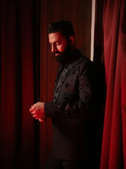 A dramatic shot of a client in a custom black bandhgala with sparkling shoulder embellishments. This outfit was designed for a high-impact look at an evening celebration.