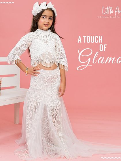 A touch of glamour is added to this white lace lehenga with a long, flowing train, making it a truly memorable outfit.