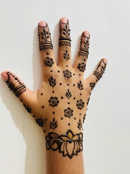 A simple yet full-looking design with a lotus wristband and scattered floral and leafy motifs across the hand.