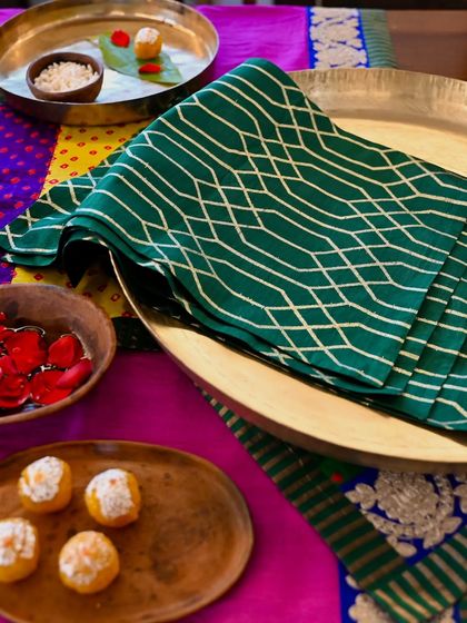 The green brocade placemat, a perfect complement to the colorful Bandhani runner and silk tablecloth.