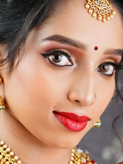 A vibrant, high-impact beauty shot perfect for a modeling portfolio or a jewelry brand campaign. The direct eye contact, flawless makeup, and stunning gold temple jewelry are captured with crisp detail and clarity.