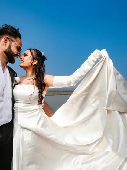 A beautiful portrait against the open water. The bride's dress catches the wind as they share a quiet look, creating a sense of romance and freedom.
