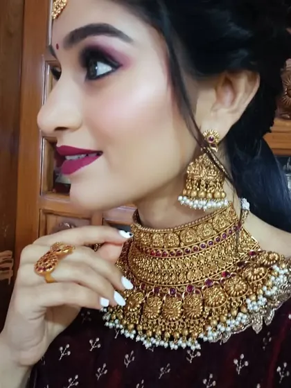 A side profile close-up, giving a detailed view of the intricate design of the temple choker and matching jhumkas.