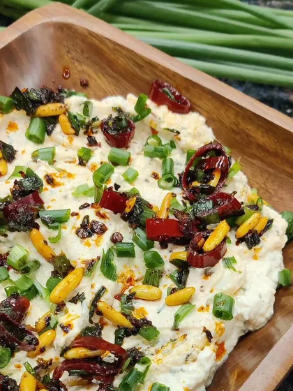 A close-up of our creamy whipped pinenut feta dip. Topped with sun-dried tomatoes, chili oil, and fresh spring onions, this dip is a testament to our commitment to fresh, flavorful, and homemade ingredients.