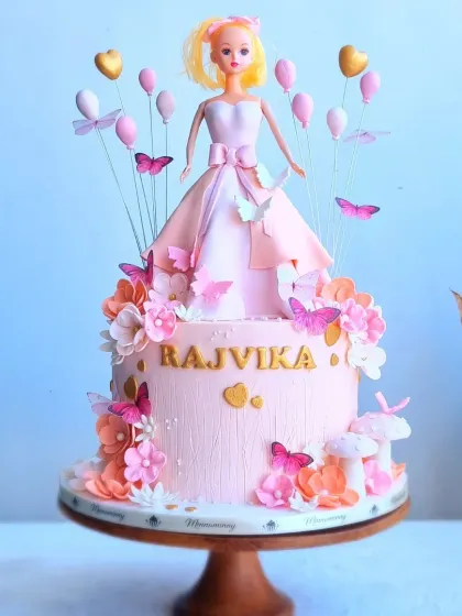 A full view of the elaborate Barbie cake with a buttercream skirt and balloon toppers.
