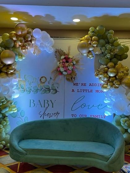 A wider view of the elegant baby shower setup, showing the green sofa placed for guests to take pictures.