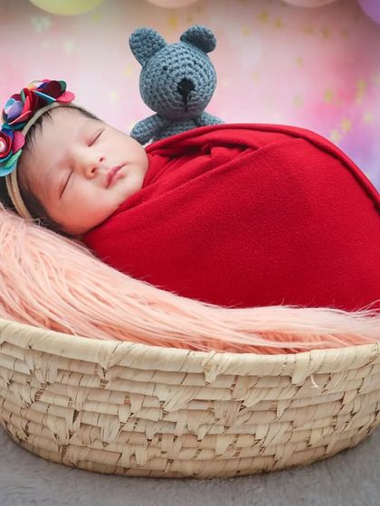 A wider shot of the same setup, showing the baby nestled in a basket against a dreamy, colorful backdrop.