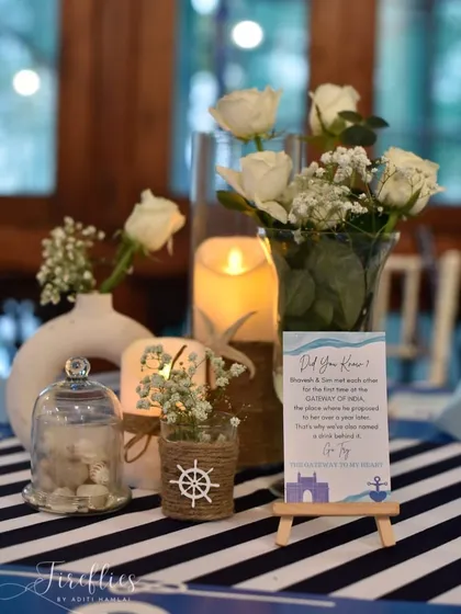 A centerpiece for the nautical theme, featuring a miniature ship's wheel, seashells, and a card sharing a fun fact about the couple's story.