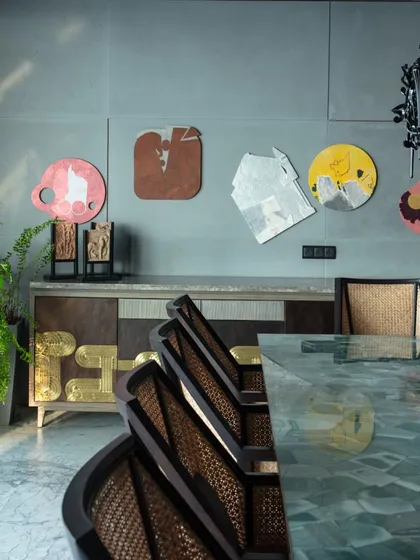 A close-up of the dining area at 'The 42, Kolkata', showing our custom cane-woven chairs and a sideboard featuring Thathera metalwork. The space is a showcase of revived Indian craft techniques.