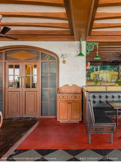 The interior of Adda 1522, featuring custom wooden doors, leather-upholstered booths, and a mix of red oxide and patterned tile flooring. Every detail contributes to the vintage pub aesthetic.