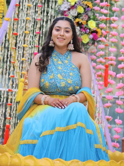 Posing on a floral swing, this bride looks absolutely beautiful. Her makeup is balanced and fresh, perfect for a vibrant pre-wedding event.