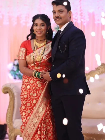 A happy couple at their reception. Her traditional red saree is paired with soft, glowing makeup for a timeless look.
