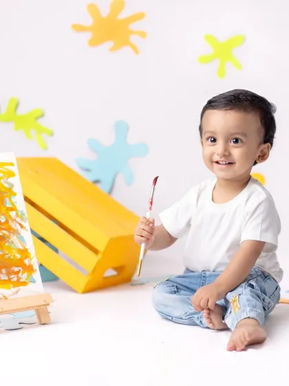 This little artist is all smiles as he poses with his paintbrush and canvas. A fun and creative milestone session.