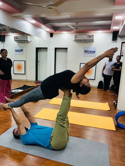 I demonstrate the base position in Acro Yoga, supporting a student in a graceful plank pose. Safety and proper technique are my top priorities in these sessions.