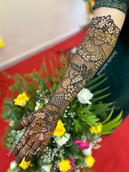 A beautiful shot of Nazreen's bridal henna against a backdrop of flowers, highlighting the artistry of the design.