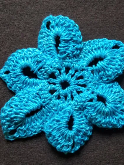A 3-inch flower-shaped crochet doily in blue.