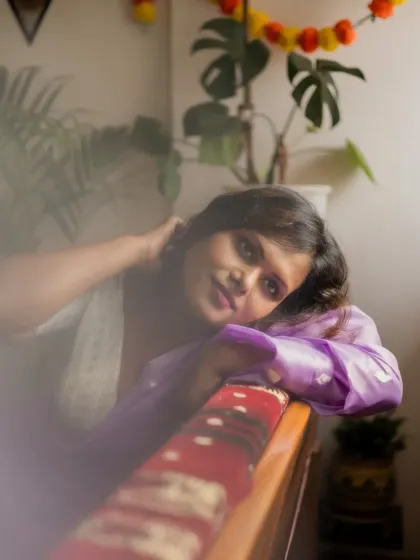 A warm, indoor portrait with festive marigold decorations in the background. The model's relaxed pose and the soft, hazy filter give the image a gentle and personal touch.