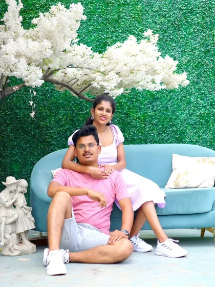 A relaxed and happy portrait on a comfortable sofa, set against a green wall and a white tree prop.