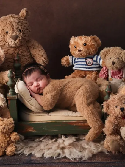 A classic pose with a cuddly twist. Here, the newborn is posed on a tiny bed, surrounded by teddy bears, creating a scene of ultimate comfort and sweetness. This is a perfect example of a themed newborn portrait.