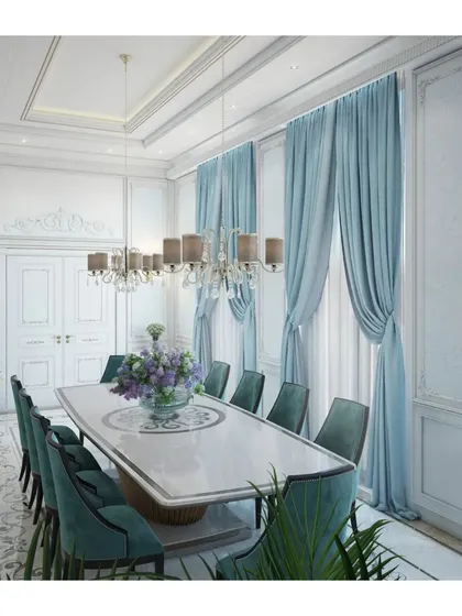 A close-up of a formal dining room in a luxury villa. The design features ornate wall paneling, plush teal velvet chairs, and a classic chandelier, creating an intimate yet sophisticated setting for dining.