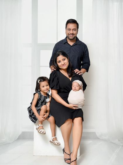 A classic, posed family portrait with a newborn and older sibling. The clean composition and coordinated outfits create a timeless image that is perfect for the family album.