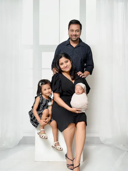 A classic, posed family portrait with a newborn and older sibling. The clean composition and coordinated outfits create a timeless image that is perfect for the family album.