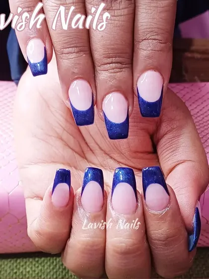 A bold French manicure with deep blue glittery tips on square-shaped nails.