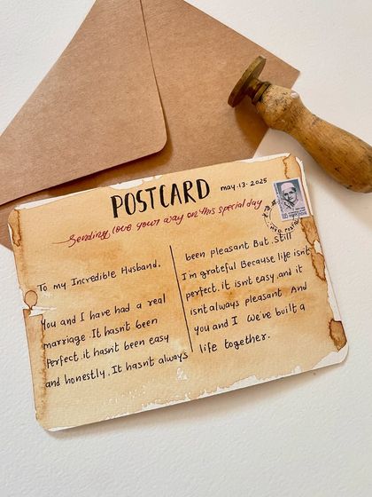This shot shows the complete postcard set: the handwritten card itself, the wax stamp used to seal it, and the simple kraft paper envelope it comes in.