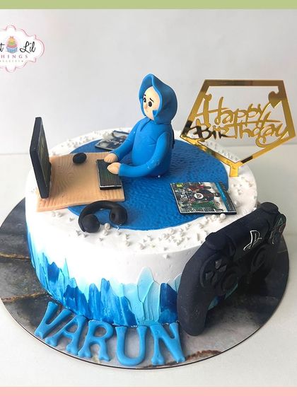 A cool gaming-themed cake for Varun, featuring a fondant figure engrossed in his laptop and a large controller on the side.