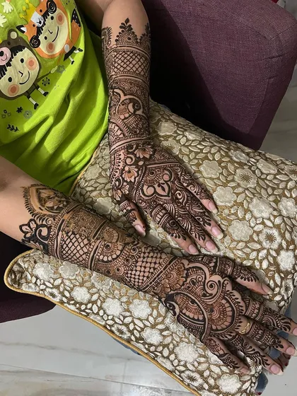 A full bridal mehndi set, shown here as the bride relaxes. The design covers the hands and arms completely, filled with traditional Indian henna art.