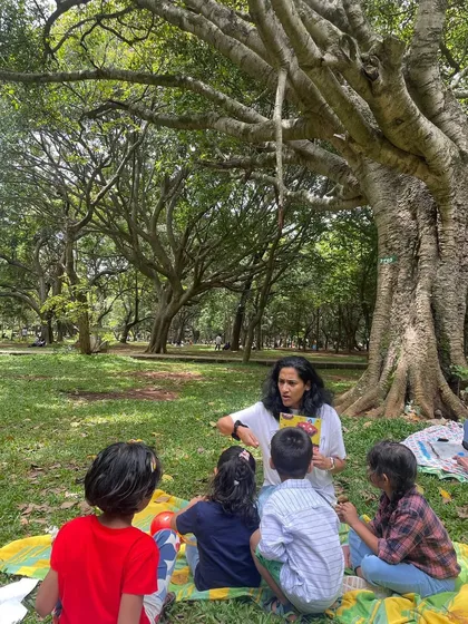 Reading under a magnificent old tree in Cubbon Park. The natural surroundings are not just a backdrop but an integral part of our storytelling experience, sparking curiosity and a love for nature.
