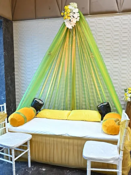 A cozy and traditional seating arrangement for the Mehendi ceremony, using a green and yellow draped canopy.